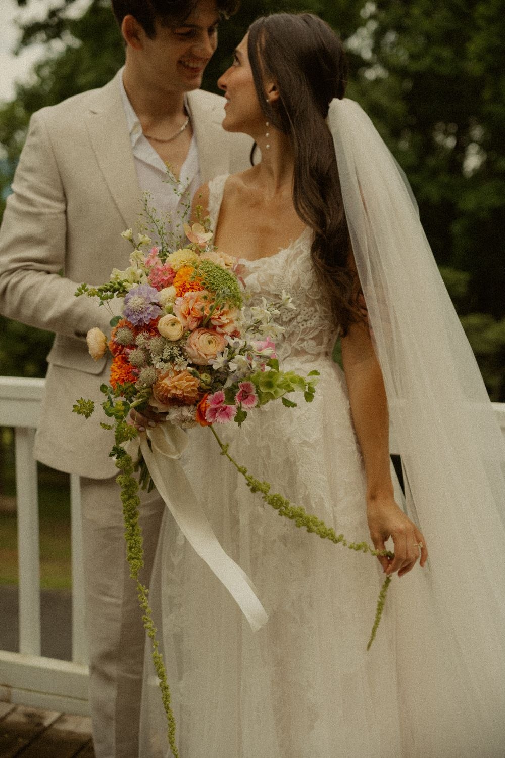 A wedding couple holding Eden’s colorful garden-style bouquet